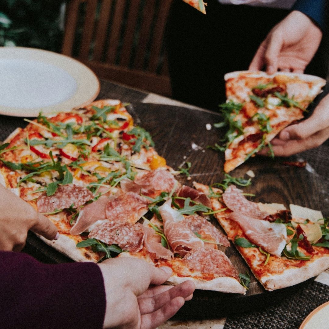 Image of people reaching for pizza slices